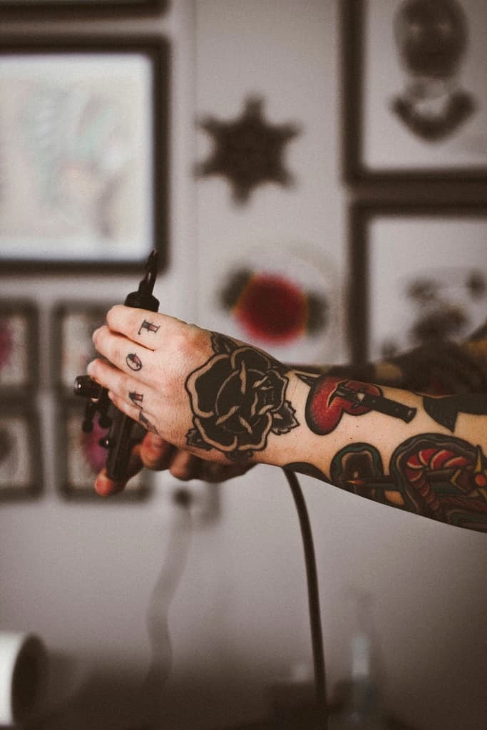 A tattoo artist's inked arm in a studio with framed art